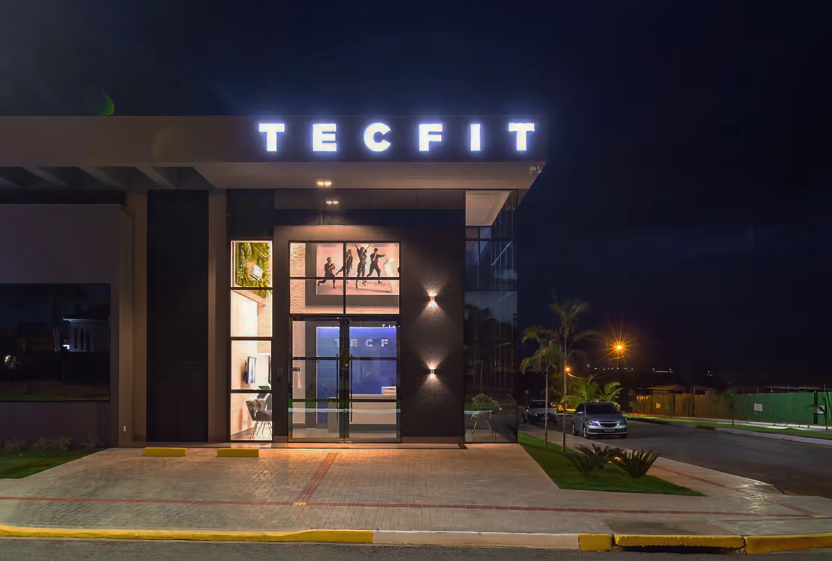 Fachada iluminada de uma unidade Tecfit à noite